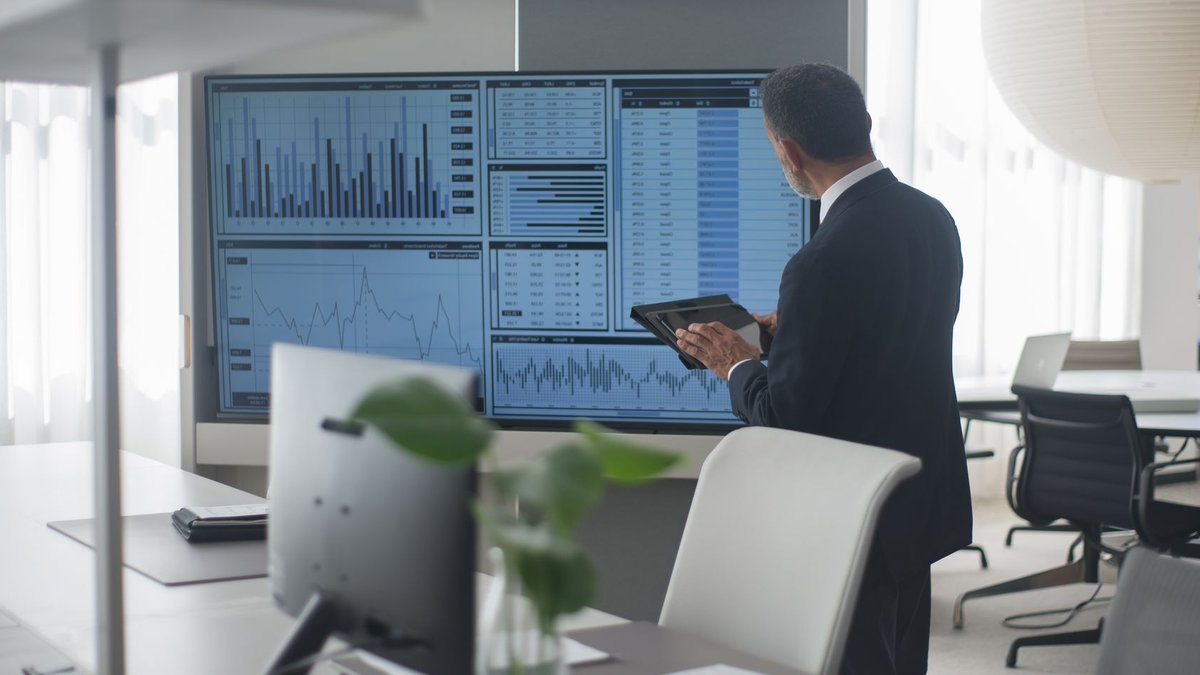 Two-Year Fixes Prevent Due Diligence Deal Failures Professional in suit analyzing financial data on screens in a modern office setting.