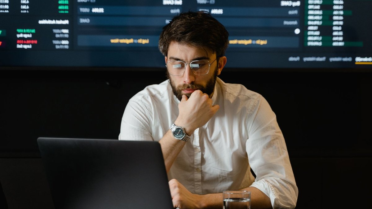Act-On unveils ready-made marketing tools for banks A man intensely analyzing stock market data on a laptop in an office setting.