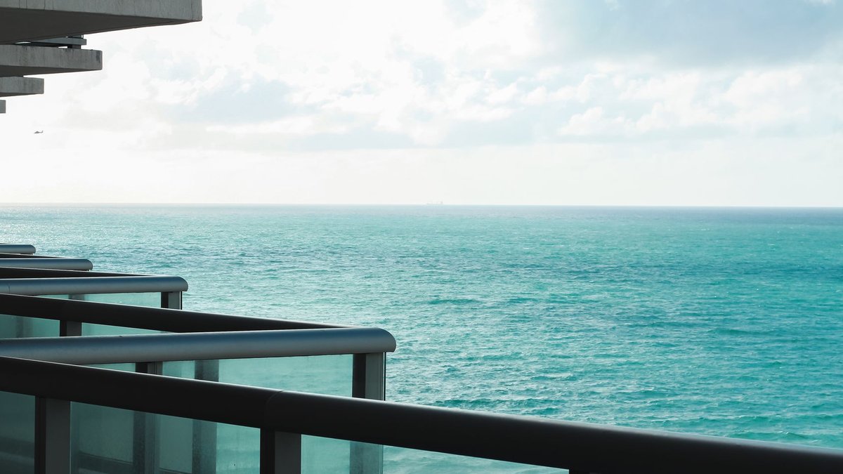 Akshaye Khanna buys Malabar Hill apartment Modern apartment balcony overlooking a serene ocean view on a sunny day.