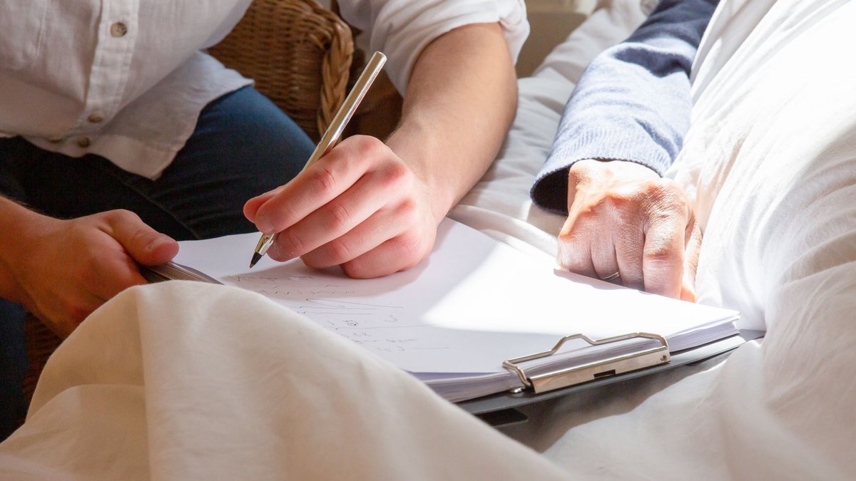 A caregiver's supportive interaction with a senior in a sunlit room, highlighting care and connection.