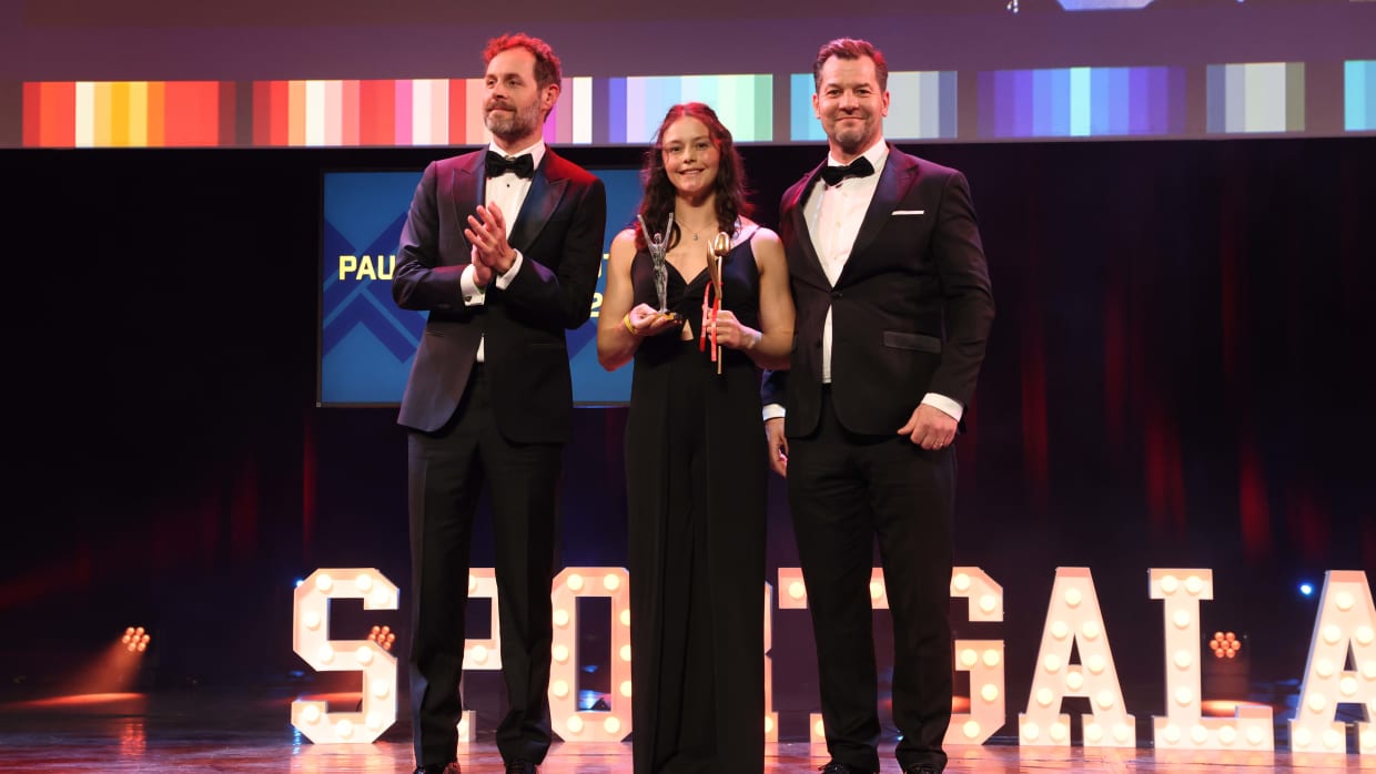 Elze Gerts ontvangt de prijs van echtgenoot van Paulien van Deutekom Kay van der Kooi (links) en broer Roland van Deutekom (rechts).
