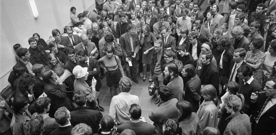 Een sympathiserende docent spreekt studenten toe in de hal van de Oudemanhuispoort