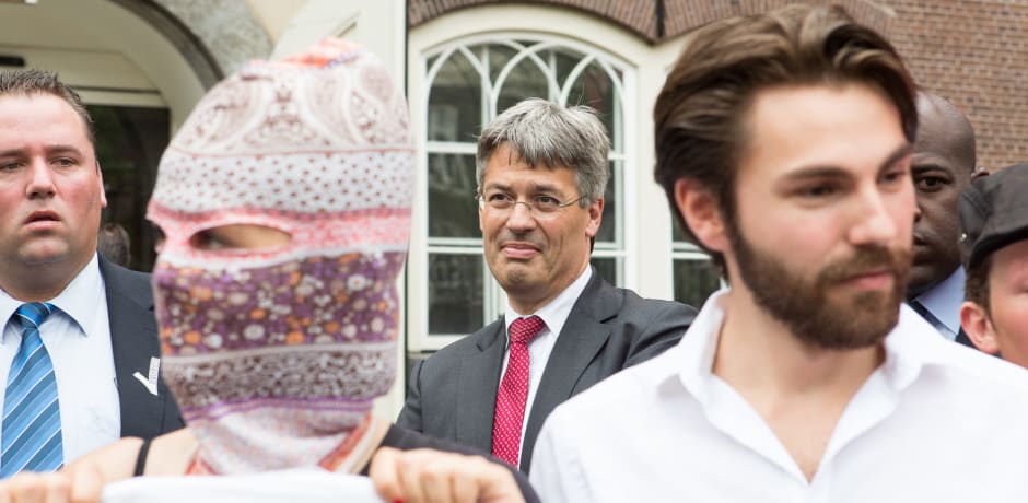 Een actievoerder met een rood vierkantje blokkeert de ingang van de aula tijdens de opening van het Academisch Jaar in 2015