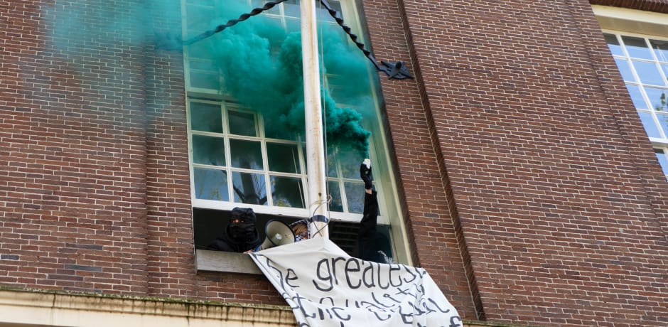 De betogers in het Maagdenhuis ontsteken een rookbom in een kleur van de Palestijnse vlag.