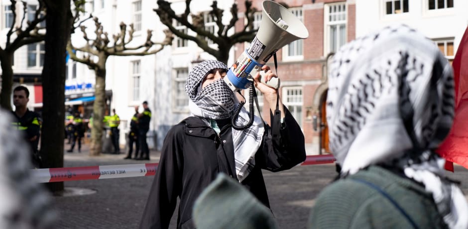 Een van de demonstranten moedigt de menigte buiten aan met een megafoon.