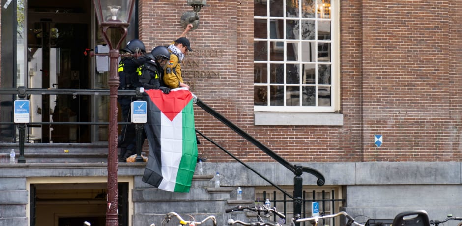  Een demonstrant steekt zijn vuist in de lucht terwijl hij door het arrestatieteam uit het Maagdenhuis wordt verwijderd.