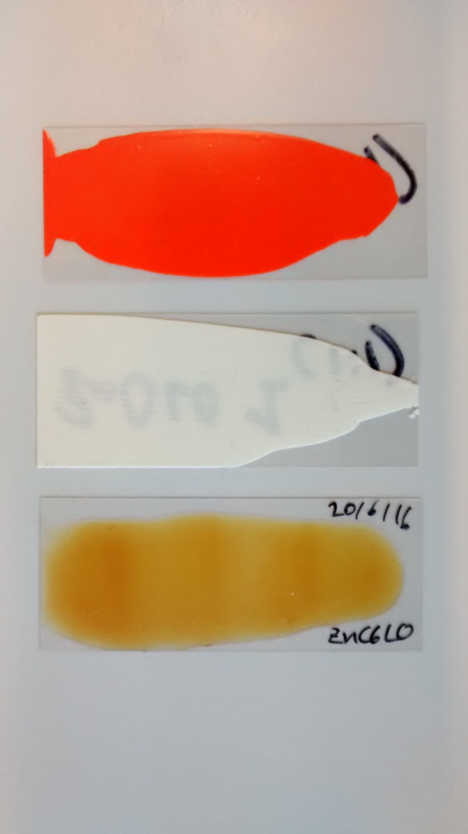 De door Hermans nagemaakte verf. Het rood/oranje- en het witte monster zijn nagemaakte verf. Het transparante gele monster is bindmiddel zonder pigment.