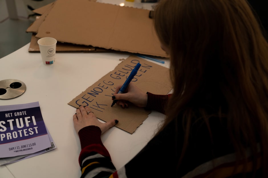 Een student maakt een protestbord tijdens de sit-in