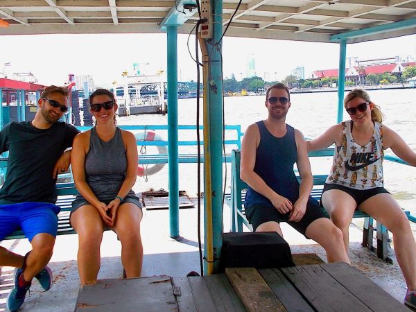 Guests on a local river ferry crossing the Chao Phraya River with Memorial Bridge in the background