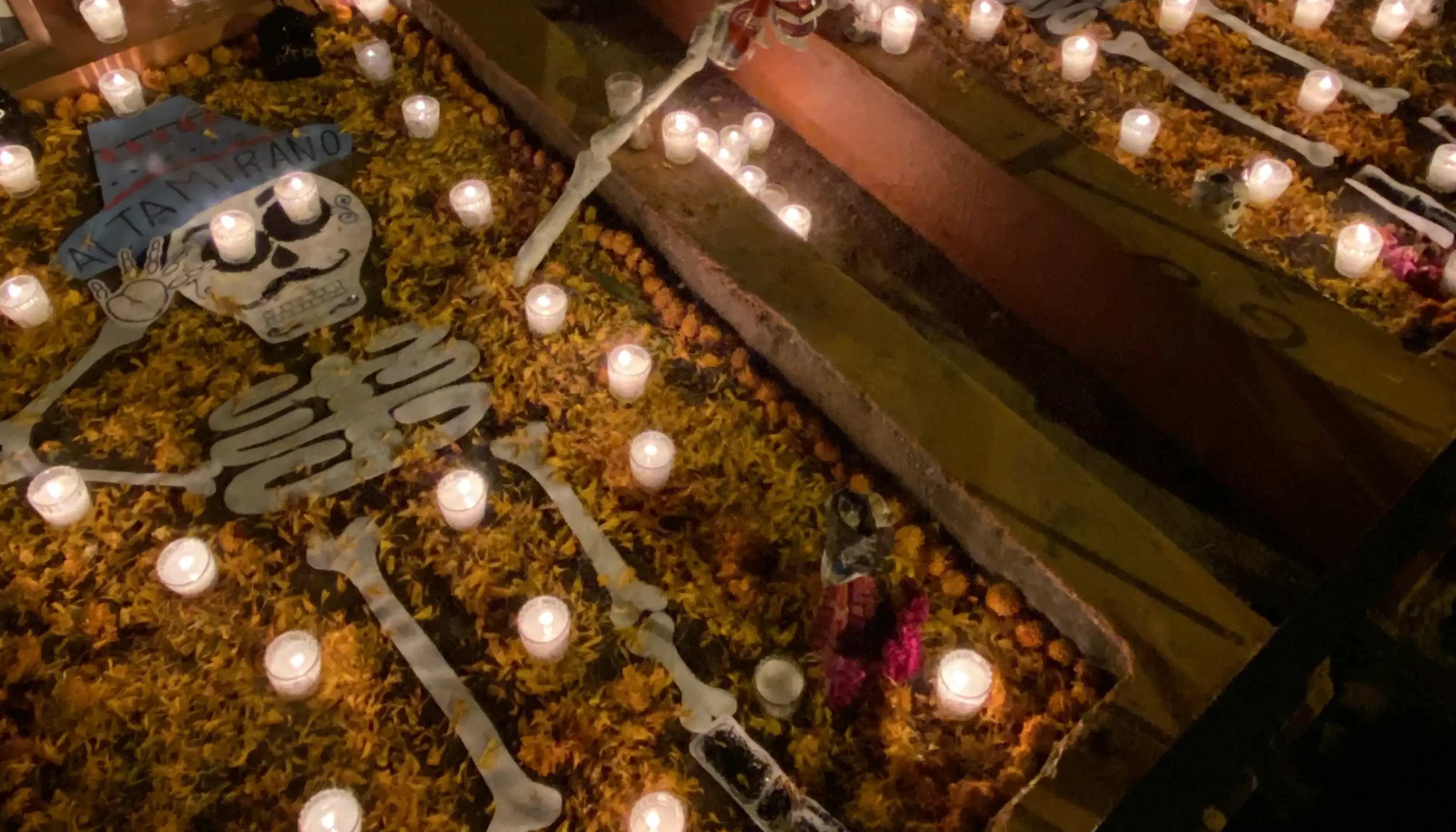Two fake skeletons laying in a float in a dark, candle-lit room