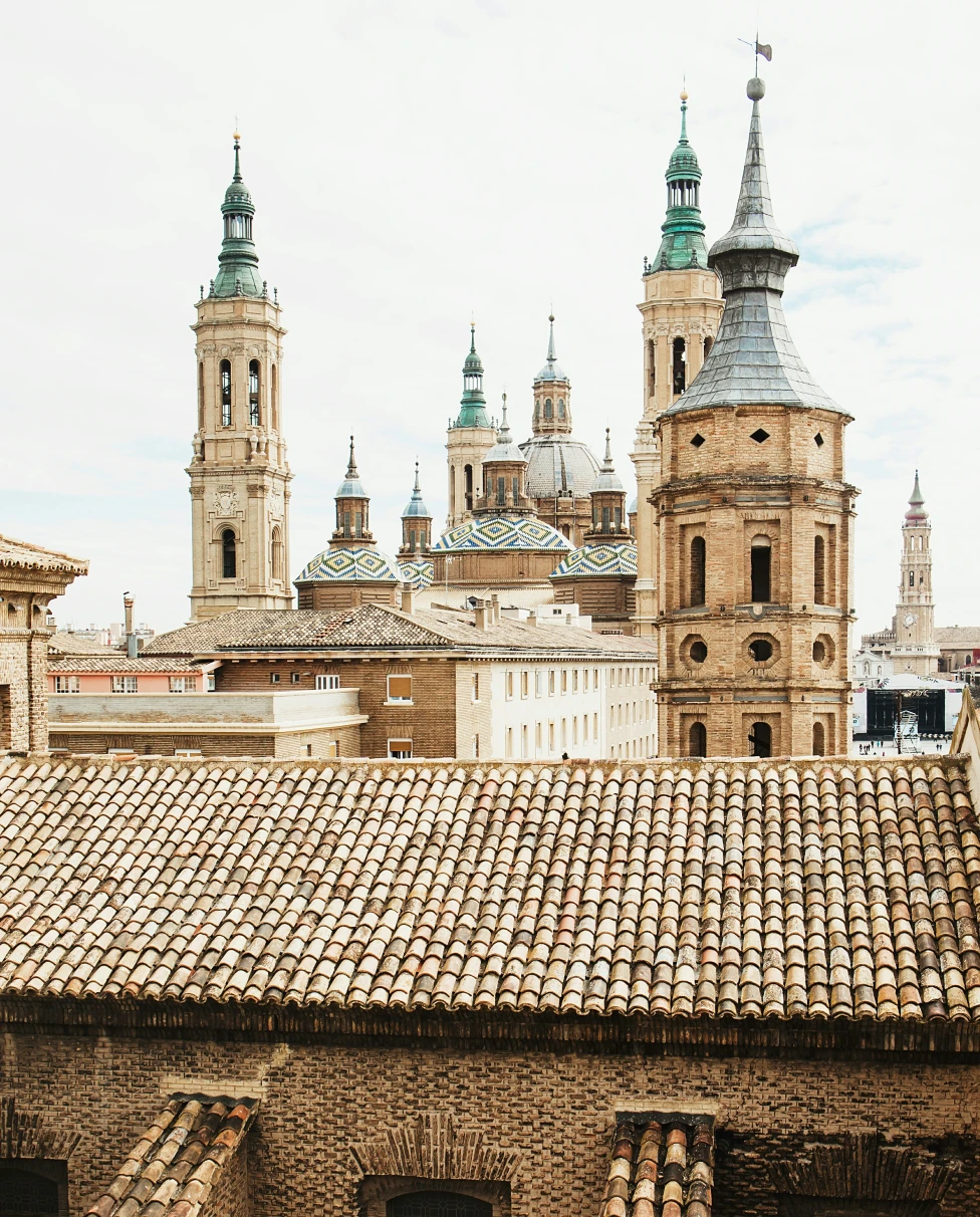 Colorful houses and apartment buildings in rows, above a stone wall in Spain.