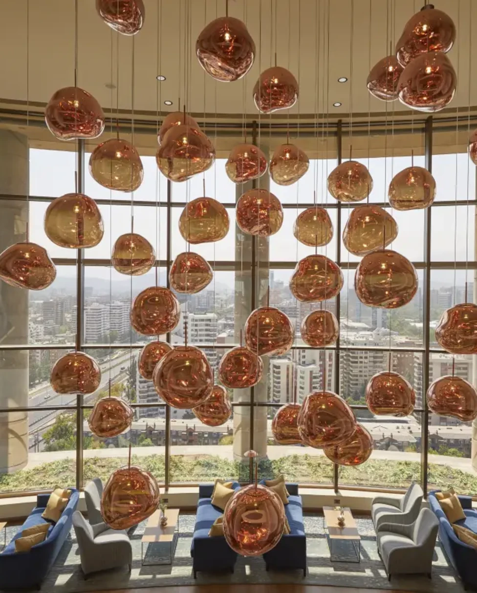 rose-gold-orb light fixtures hanging in a light-filled lobby with floor-to-ceiling windows