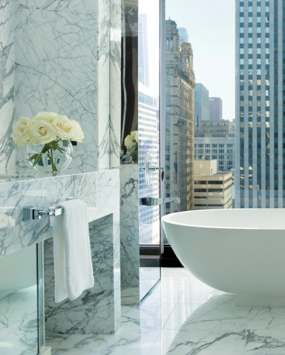 swanky marble bathroom with floor-to-ceiling windows and a large white tub