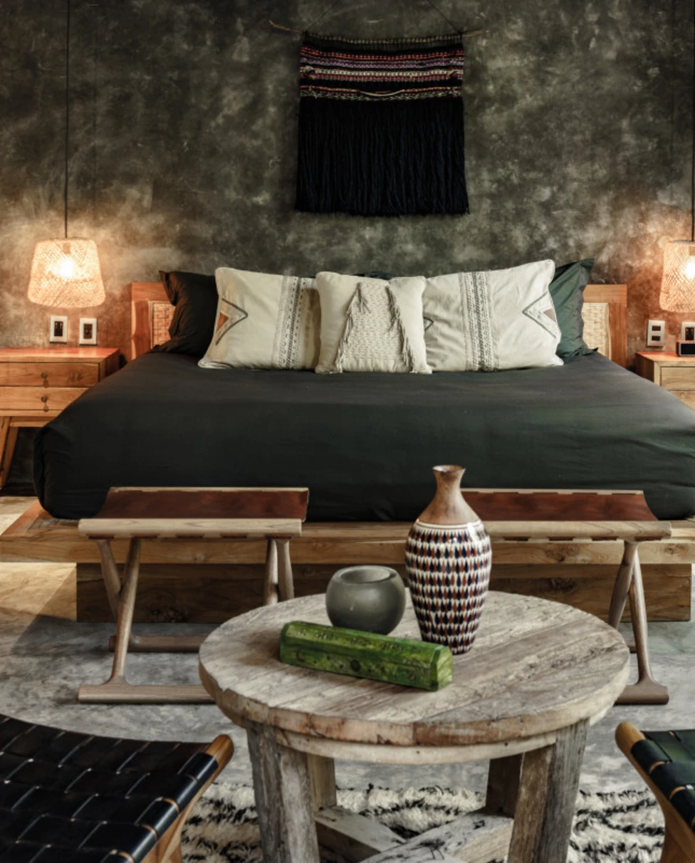 a bed with charcoal-colored bedding near artisanal artwork