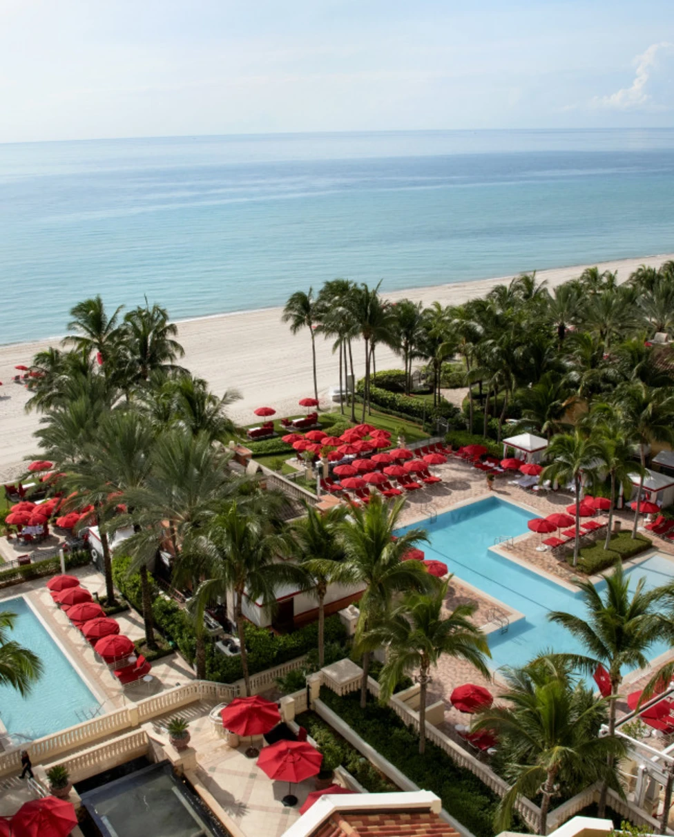 red umbrellas and loungers surround a beachfront pool