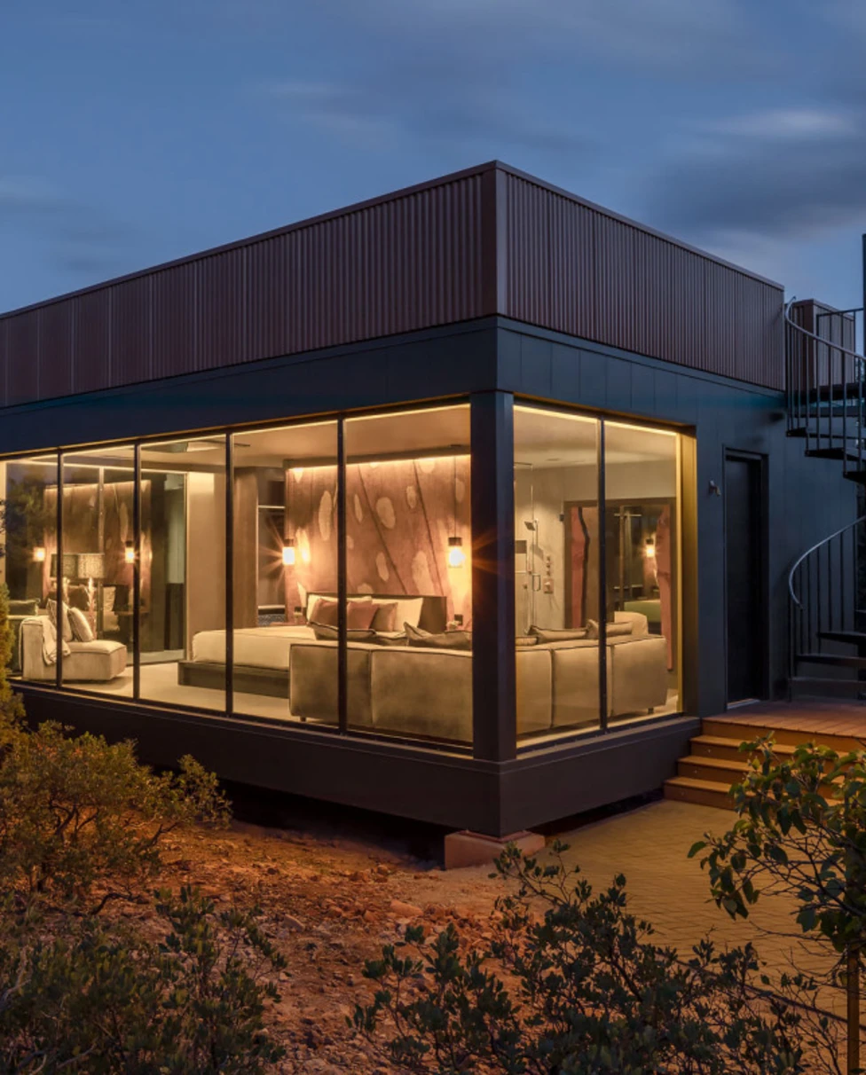 a cubic building with floor-to-ceiling windows and a spiral outdoor staircase