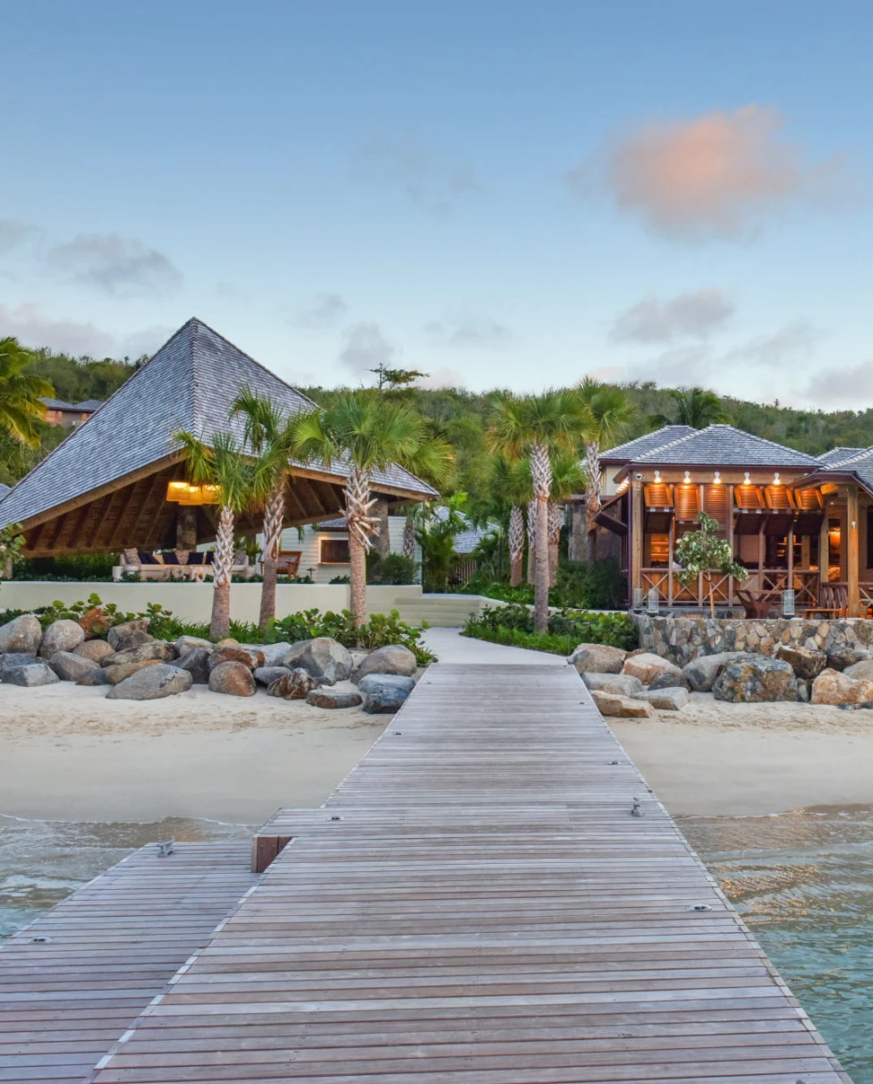 wooden pier at Rosewood Little Dixie Bay leading to a serene, open-air lobby