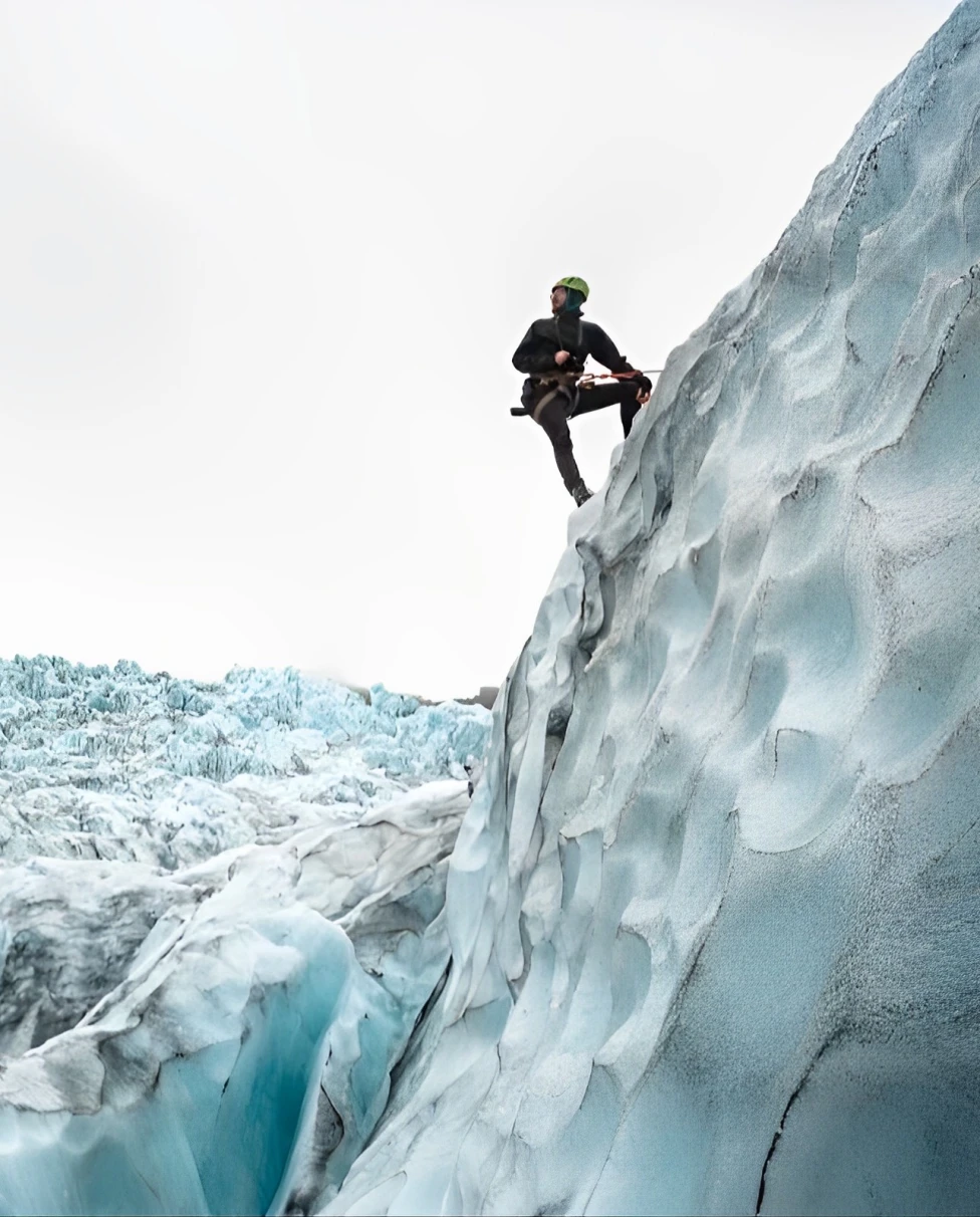 a person in all black stands on an ice cliff