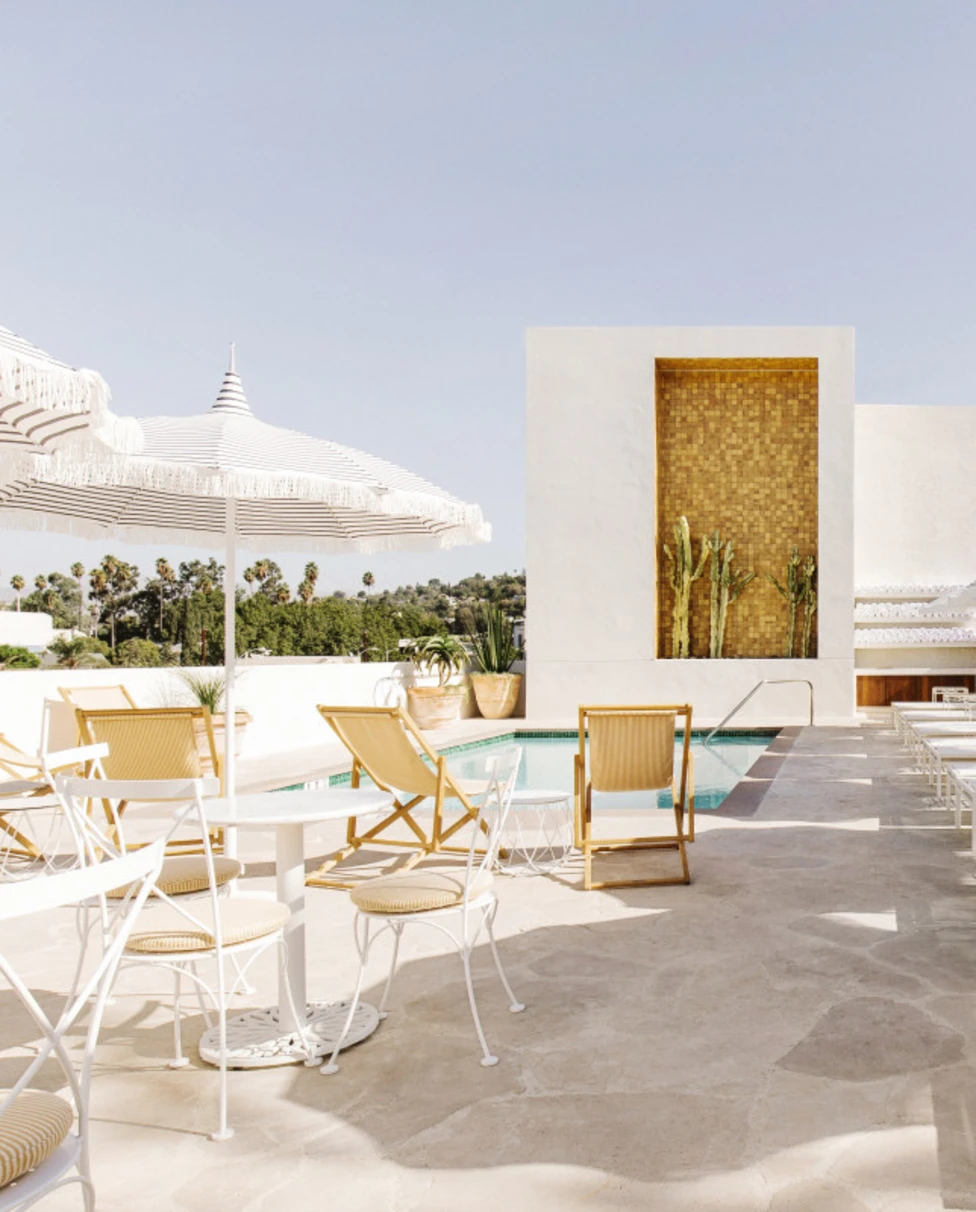 sunny pool deck with white chairs and umbrellas