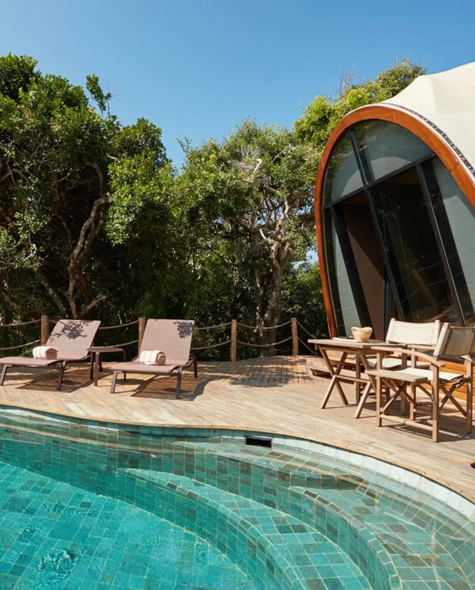 an ovular pool near a rounded tent on a wooden deck