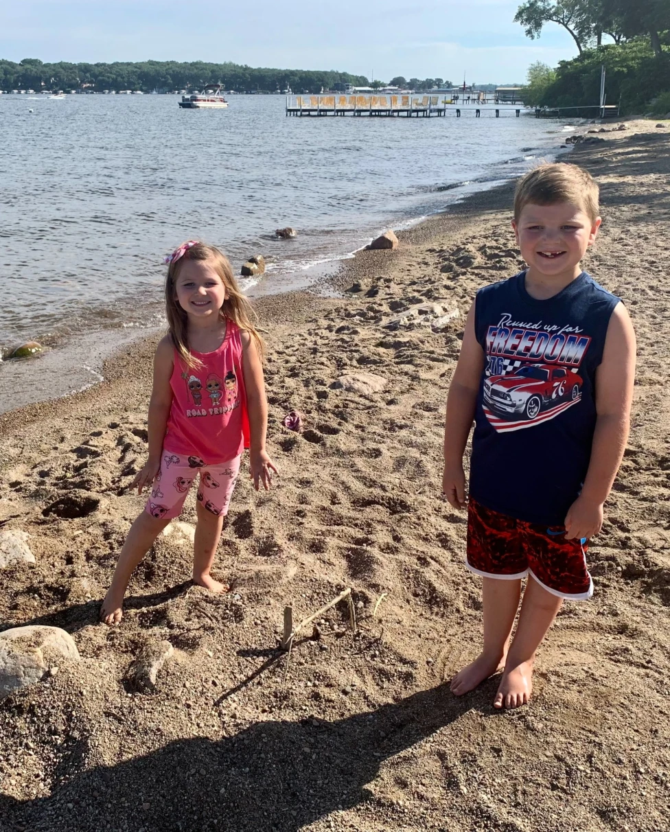Two children on a beach next to the water during the daytime