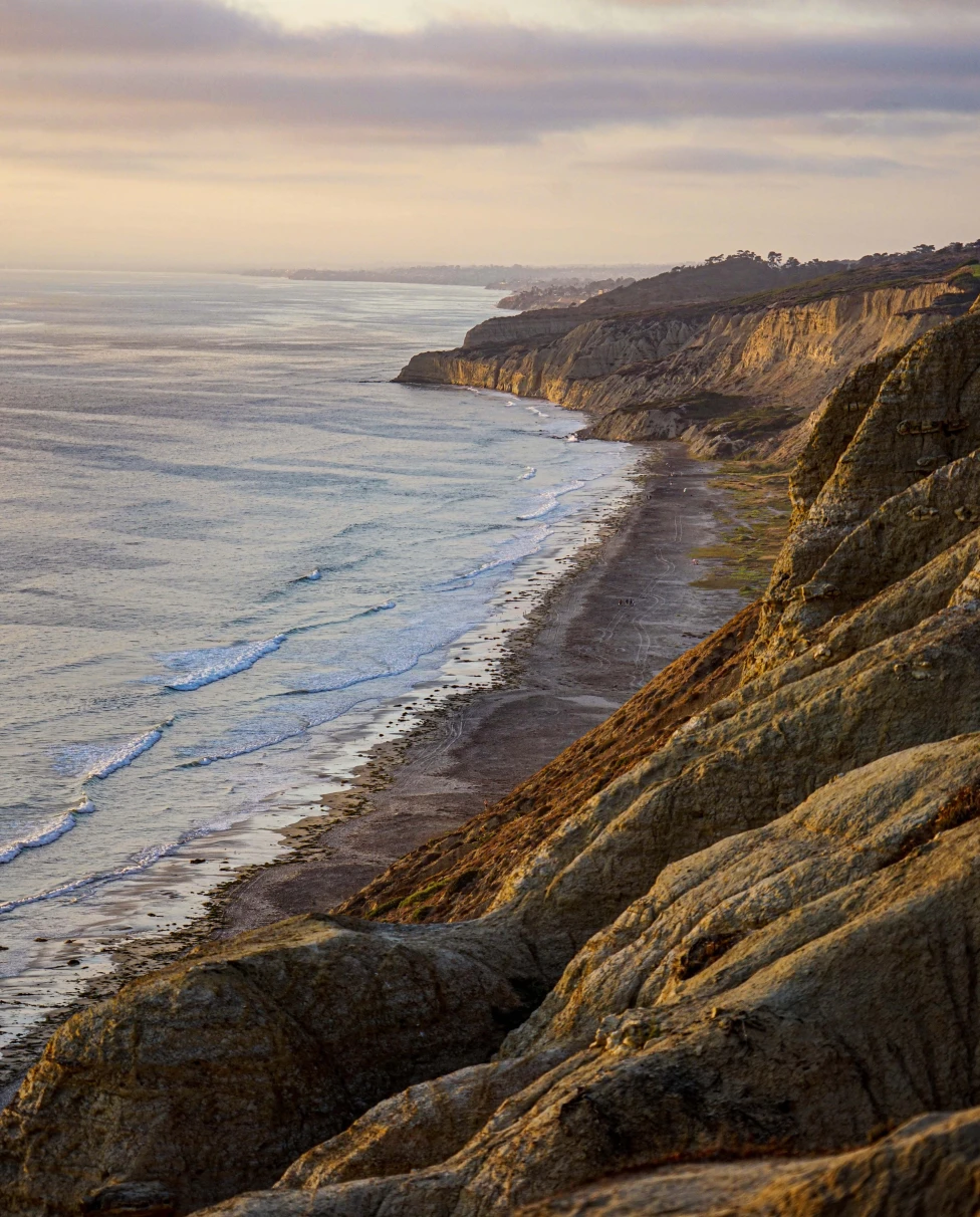 Ocean along coastline with pink and purple clouds