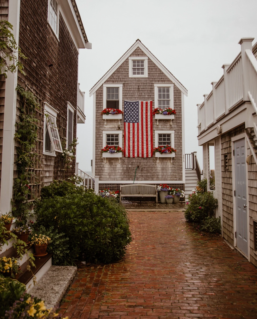 Brick alley lined with houses and American flag hanging on cloudy day