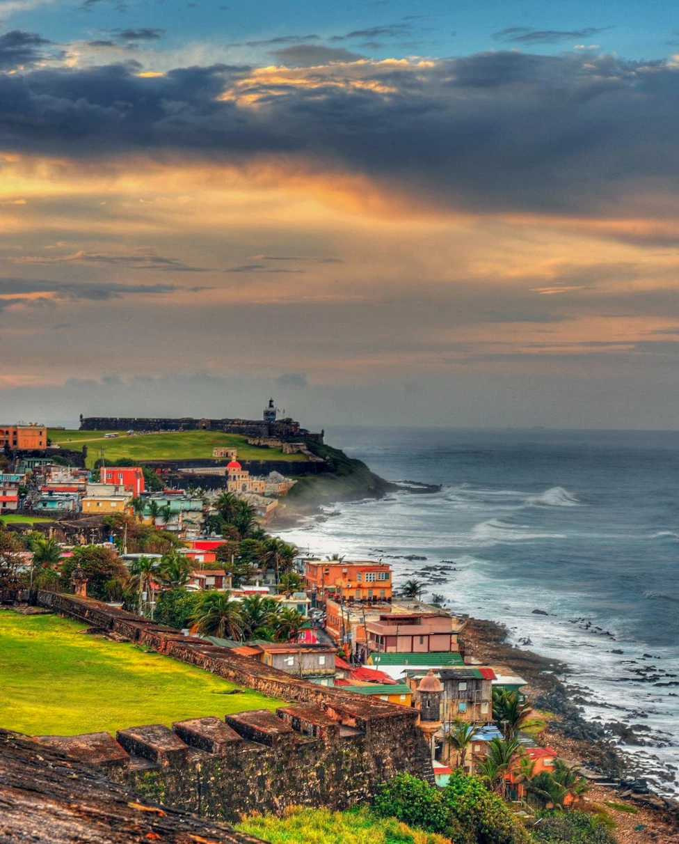 Body of water next to cliff with houses during sunset