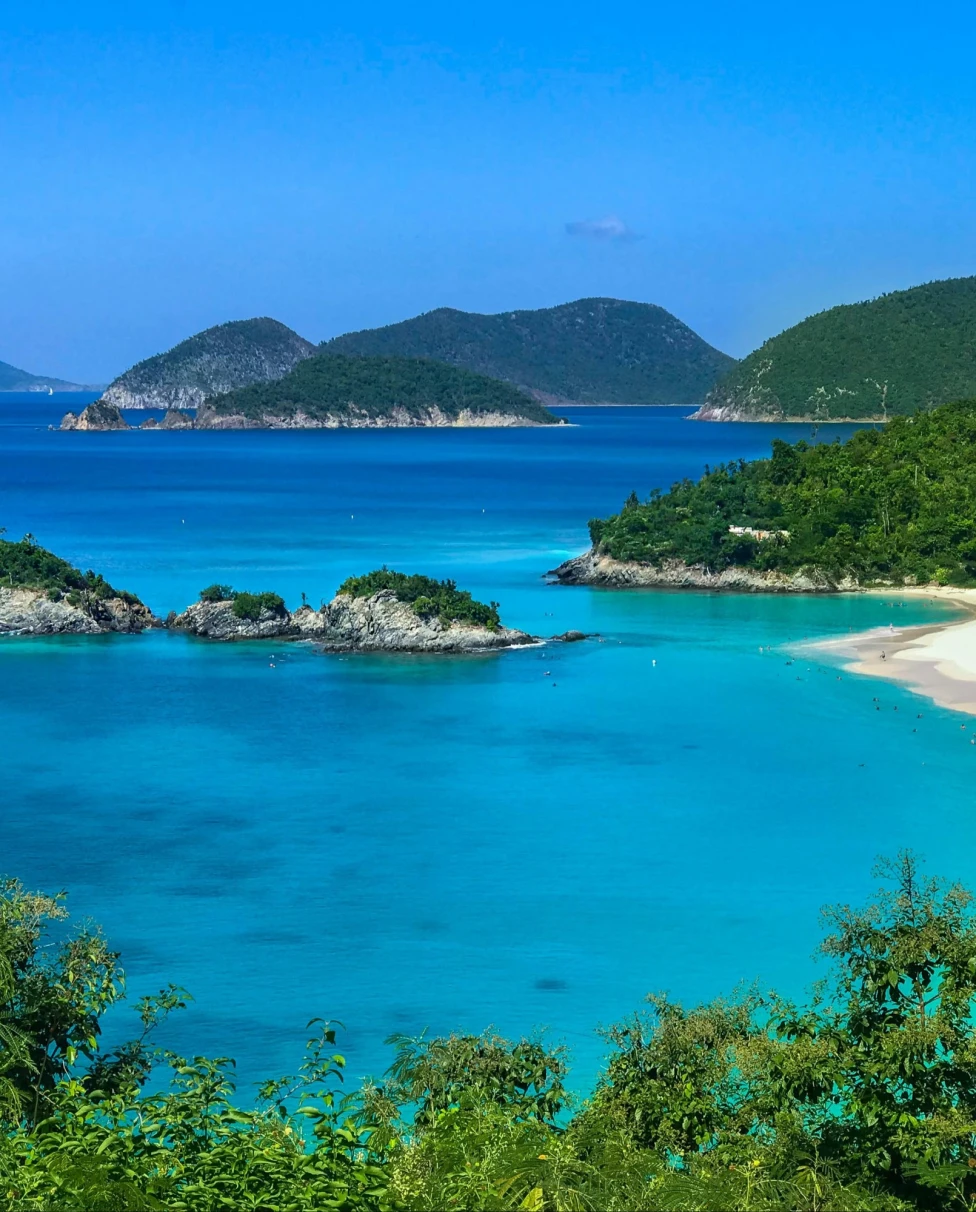 A beautiful view of bright blue water and islands covered with white rocks and trees.