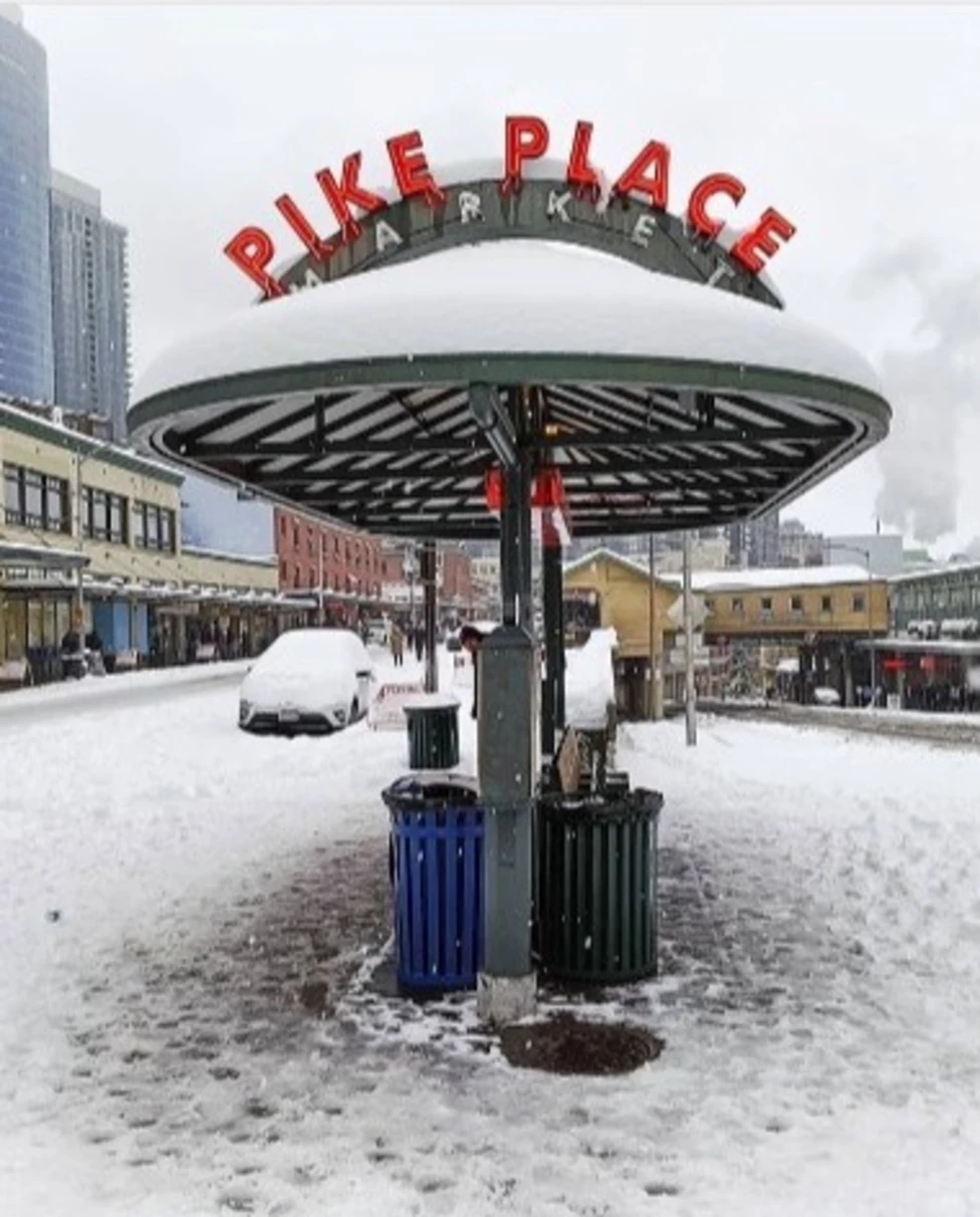 A snow-covered sign reading "Pile Place Market" during the daytime