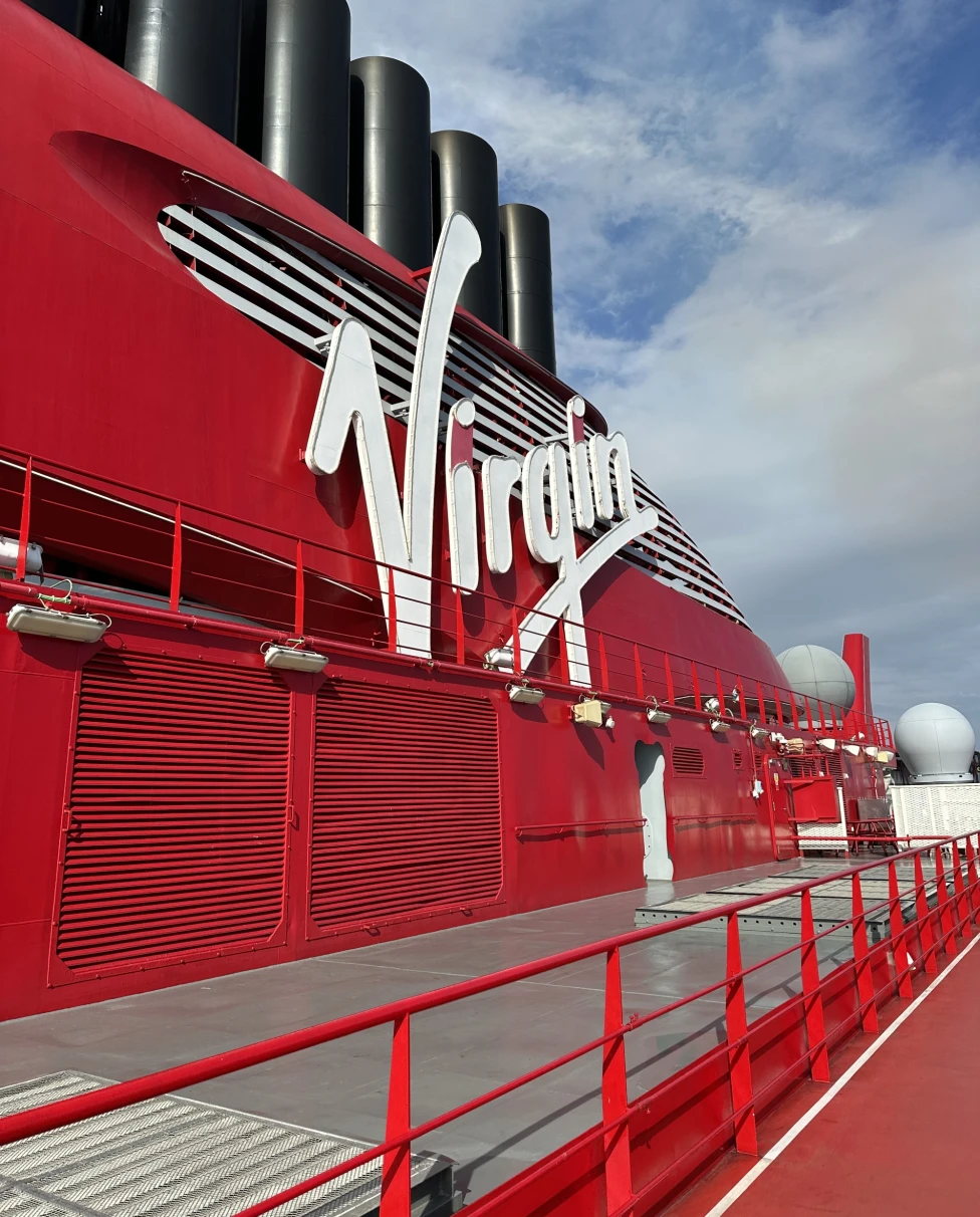 A sign of placed on a red colored cruise ship saying "Virgin".
