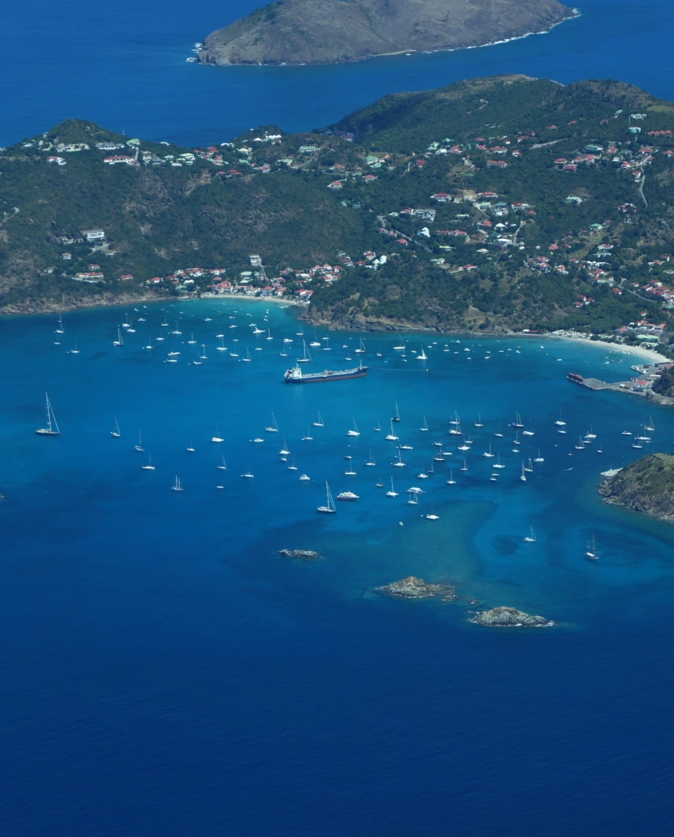 An aerial view of a small island with boat in the water.