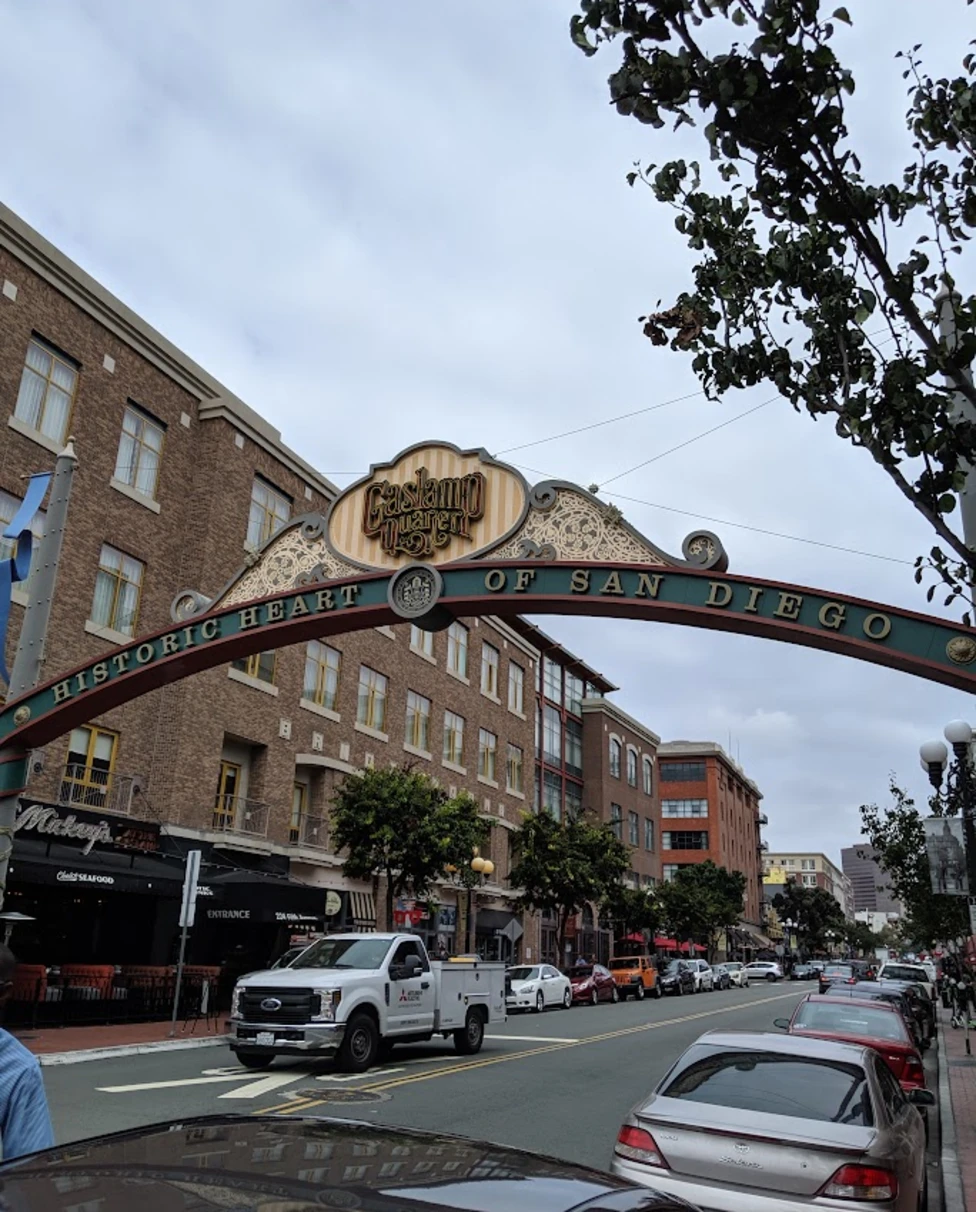 Gaslamp Quarter in Downtown San Diego is a vegan haven. Picture is of a street with cars and a "Gaslamp" arch over the center.