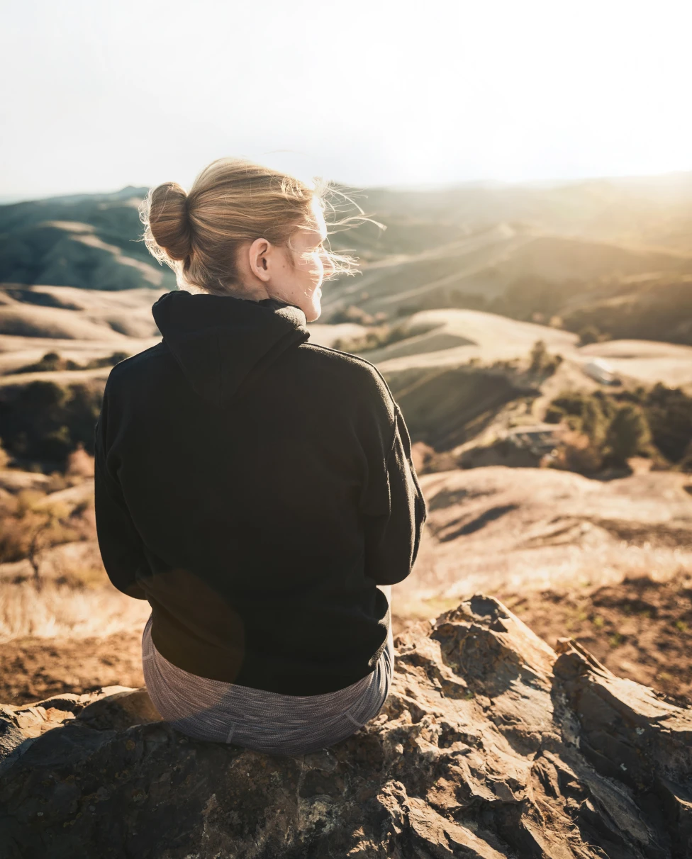 Girl sitting on a mountain.