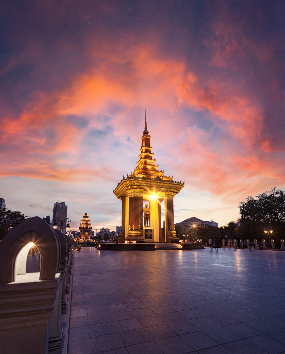 A golden-colored temple int he middle of the street at sunset time. ;