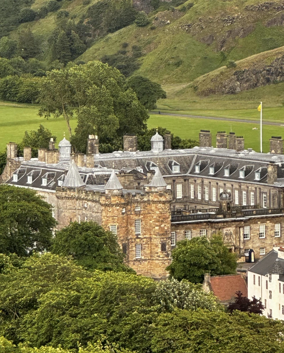 Large castle with green mountains at the back.