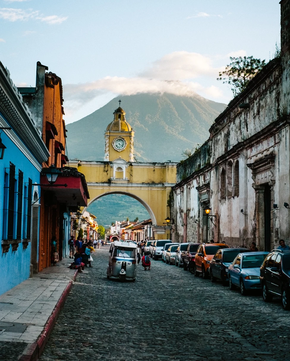cobblestone street with arch tower and mountains