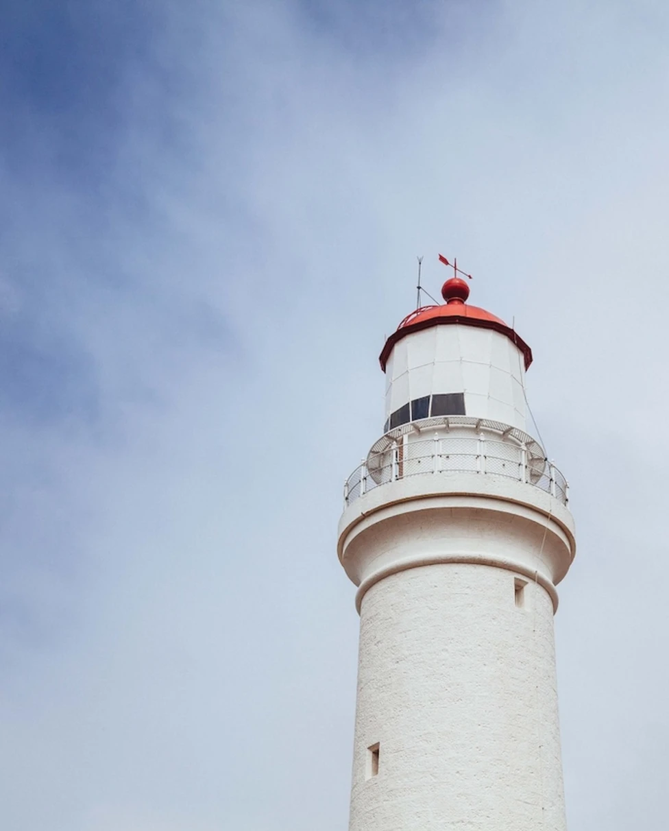low-angle shot of a red lighthouse with a red top