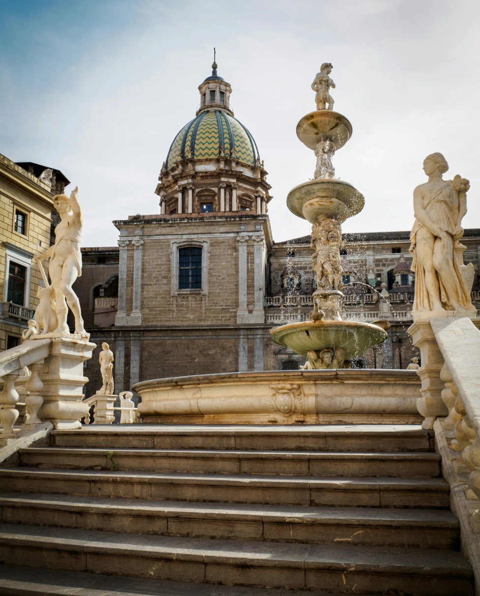 A beautiful architectural scene with a fountain, statues, and a domed building.