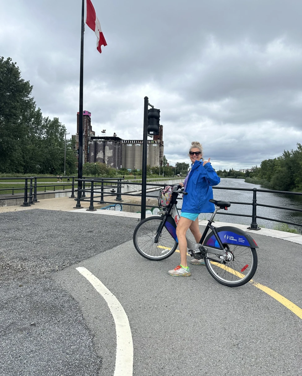 A girl posing on a bike near a Canadian flag at daytime.