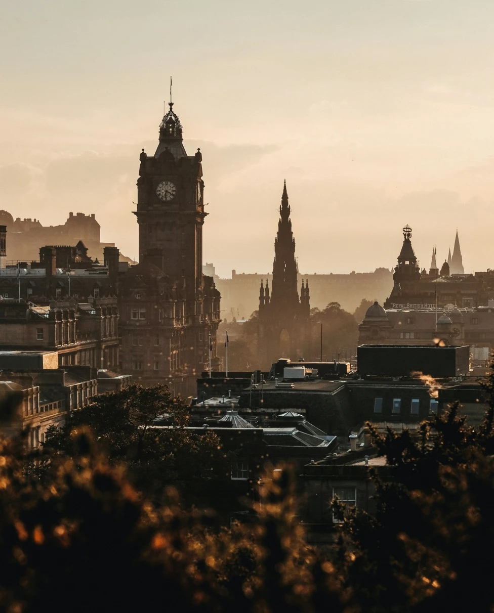 The image depicts a cityscape at sunset with historical buildings all bathed in warm light.