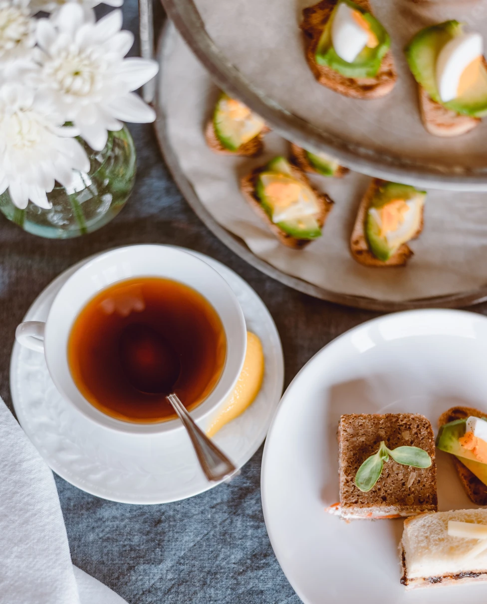 Afternoon tea featuring finger sandwiches, biscuits and black tea.