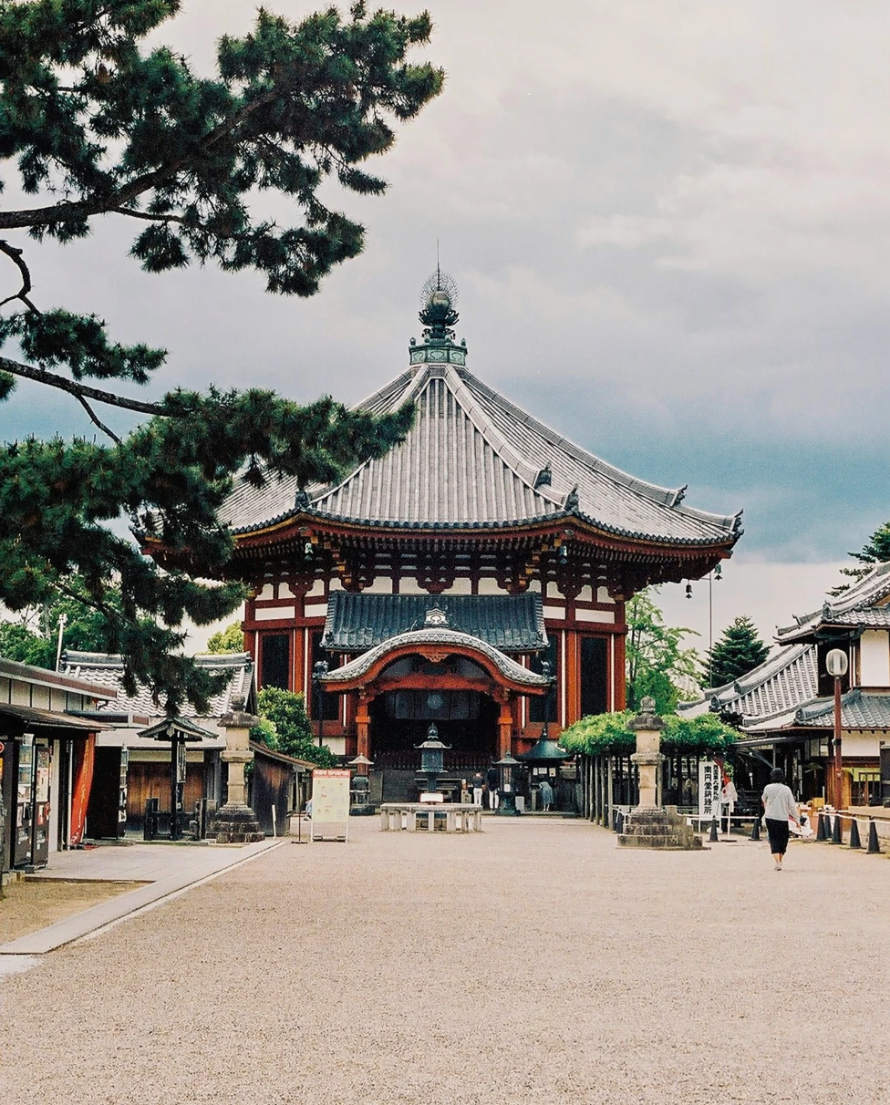 A view of a beautiful temple in Japan surrounded by trees and a cloudy sky.