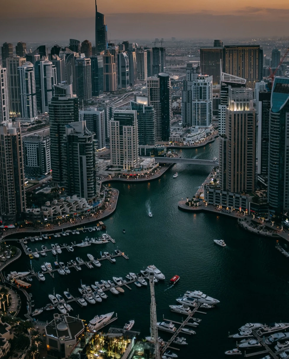 modern city on the water at sunset with skyscrapers and an active harbor
