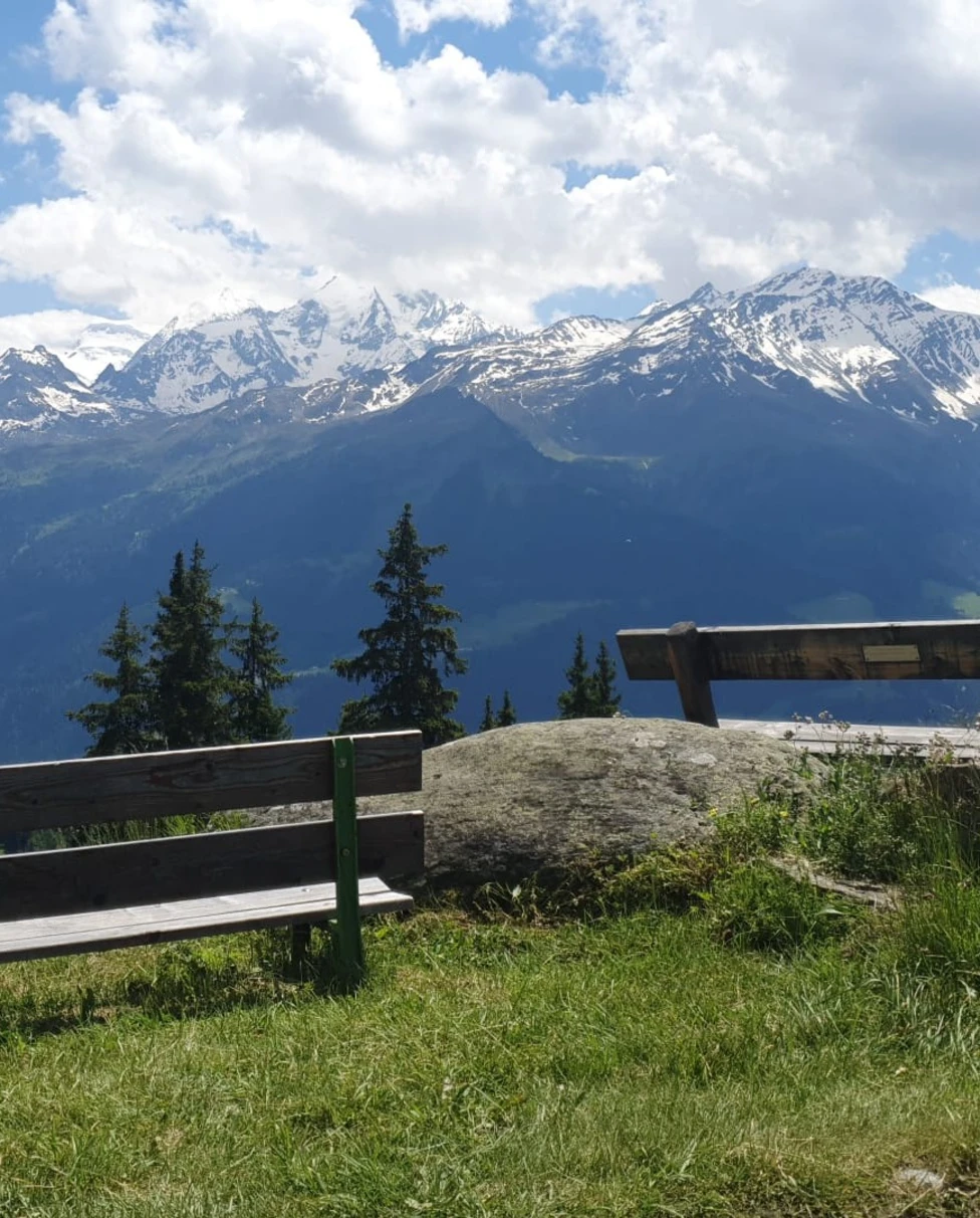 Bench with view of snow covered mountain peaks.