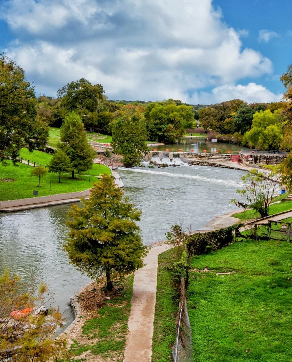 A view of a local park with a river running through it on a sunny day.