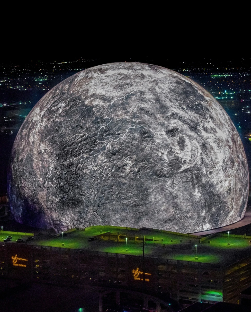 A large moon sphere over city at night.