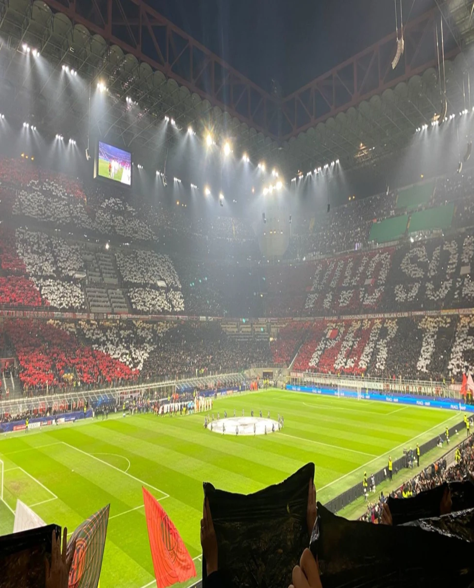 A stadium with people watching a sports game at nighttime.