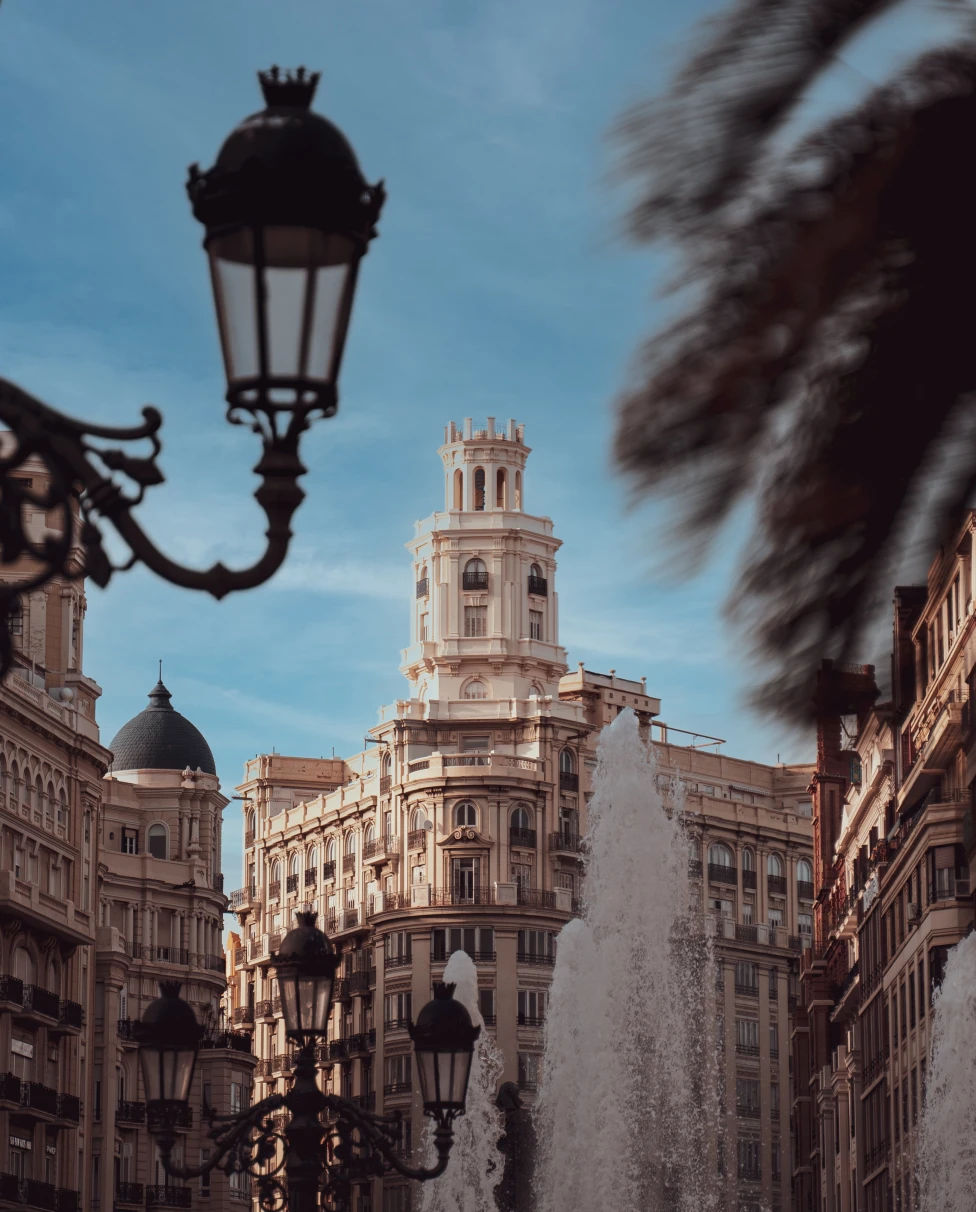 Streetlight and tree with large white building in the distance during daytime
