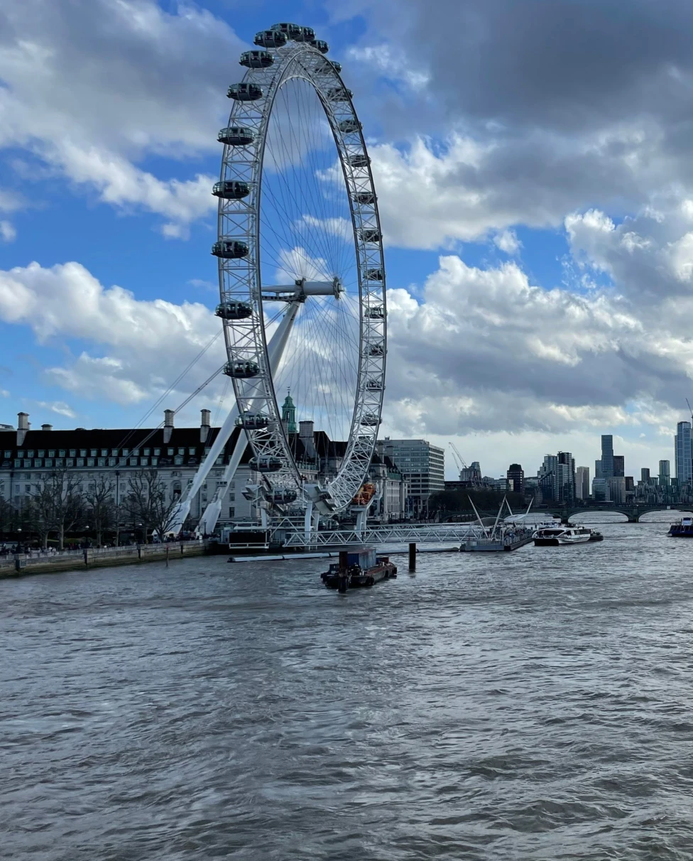 View of the London Eye on the water during a cloudy day